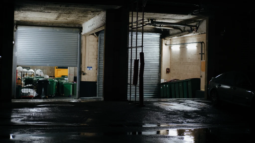 An open garage door alongside a second door that provides access to the building's dumpster section.